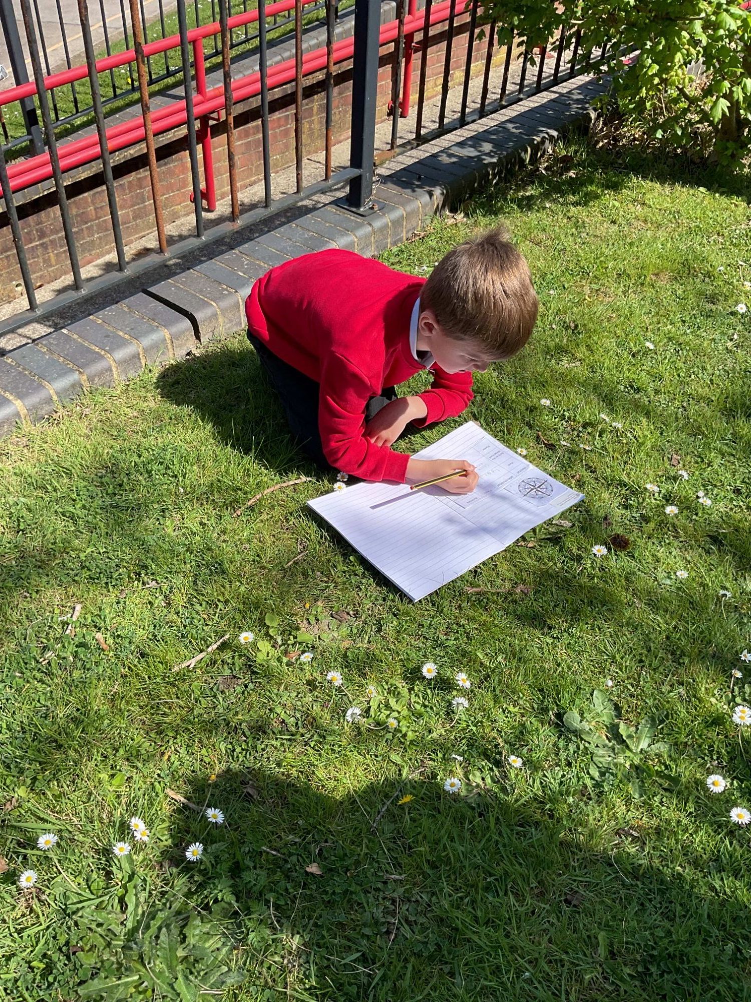 child writing in book outdoors
