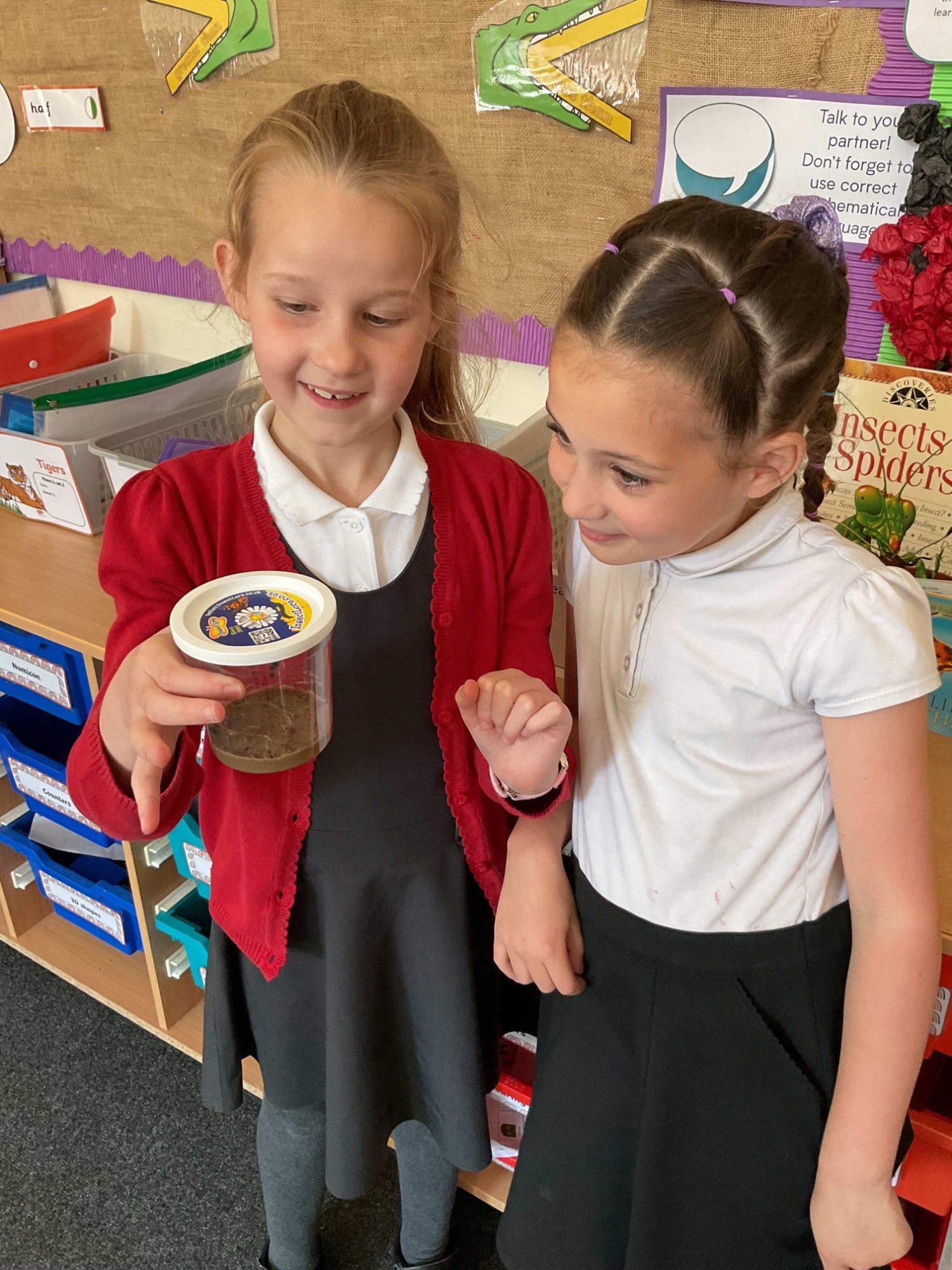 children looking at jar of caterpillars