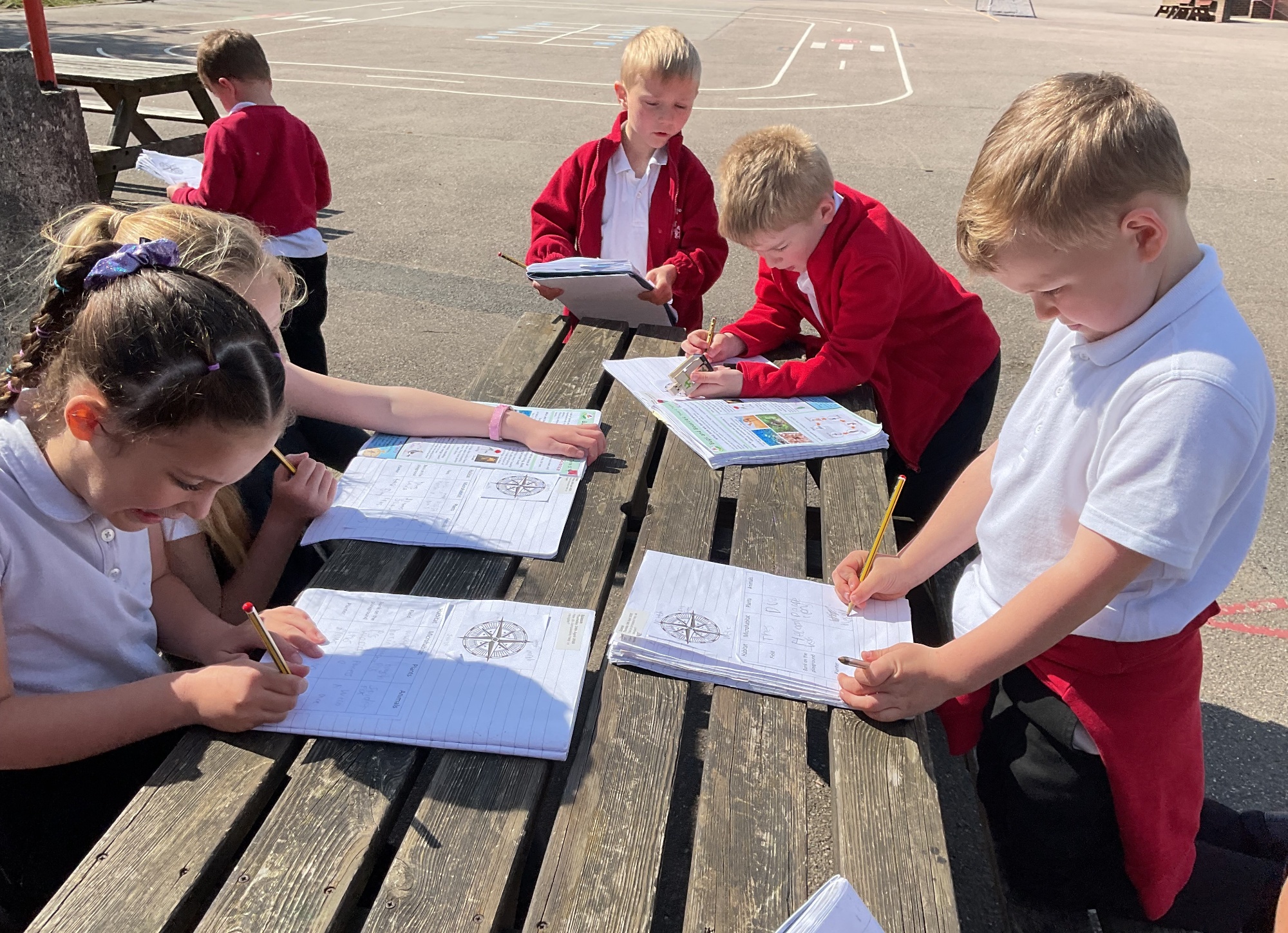 children writing at a table outdoors